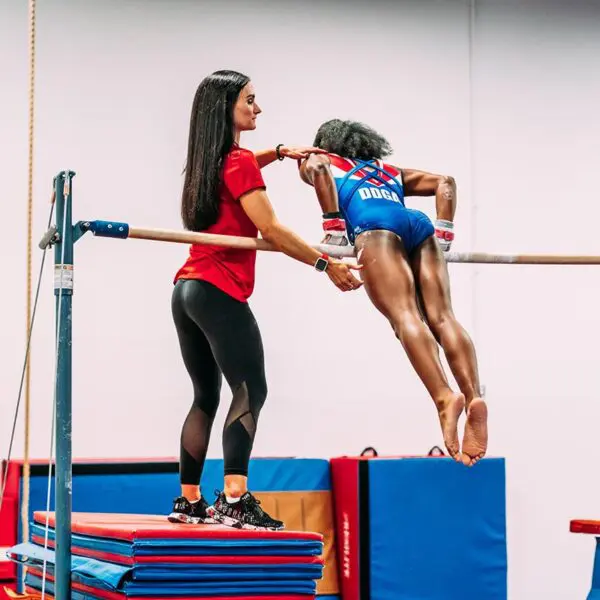 Competitive gymnast practicing with the help of a coach.