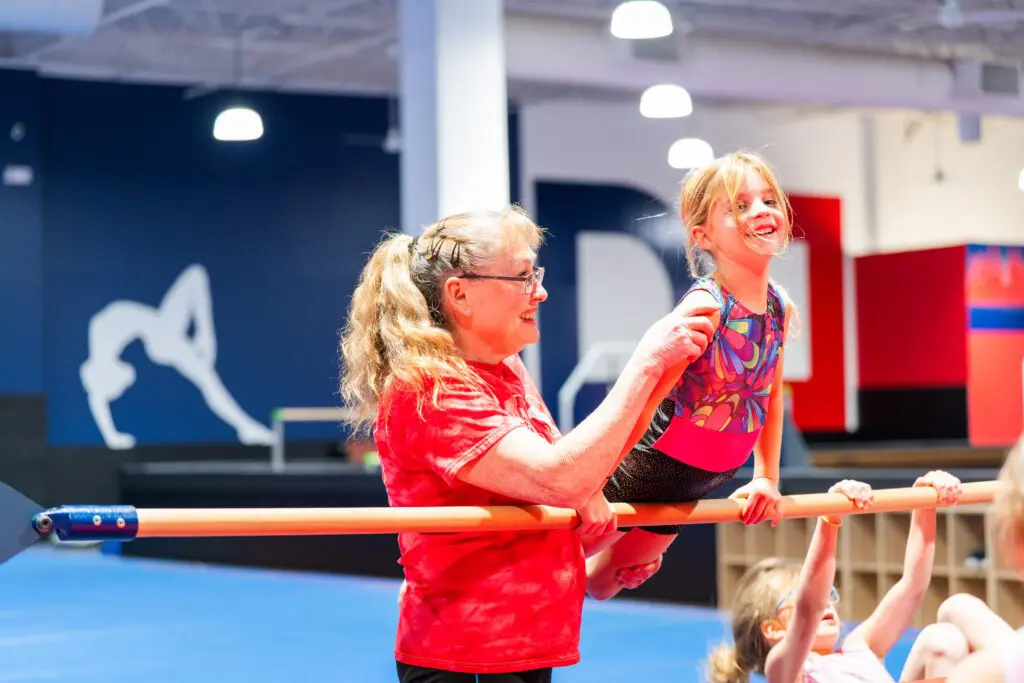 Child happy to be learning gymnastics with the help of a coach