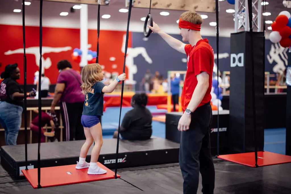 Child having gymnastics camp fun safely with a coach