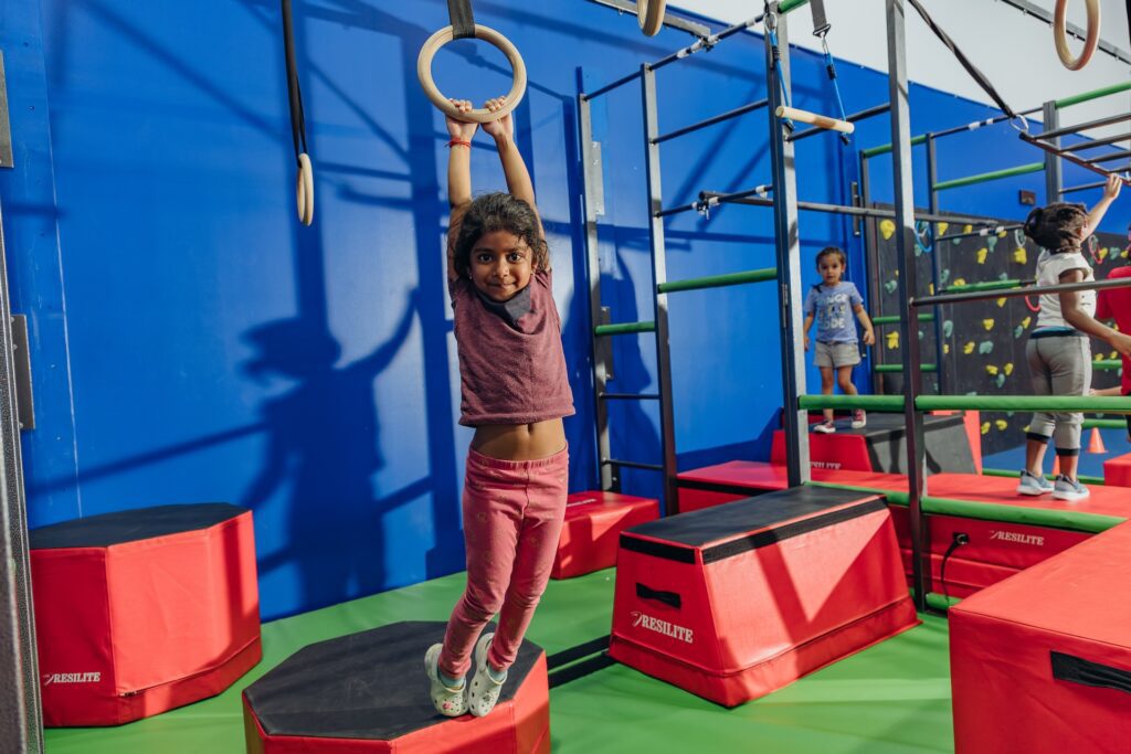 Little girl hanging on ring during gymnastics class at Dominique Dawes Academy