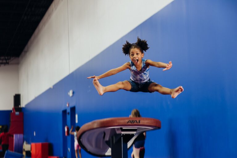 Little girl jumping in air during gymnastics class at Dominique Dawes Academy