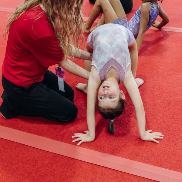 Coach spotting gymnast on back walkover