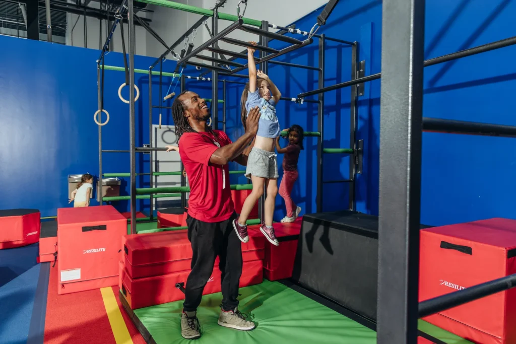 Coach spotting gymnast on bars