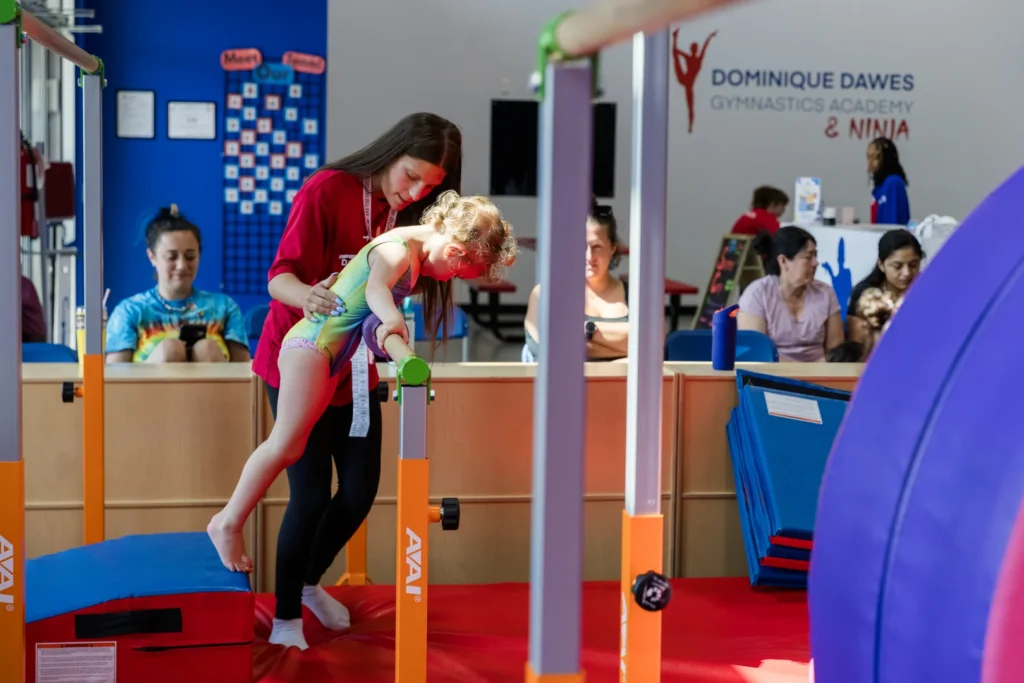 Coach training gymnast on bars