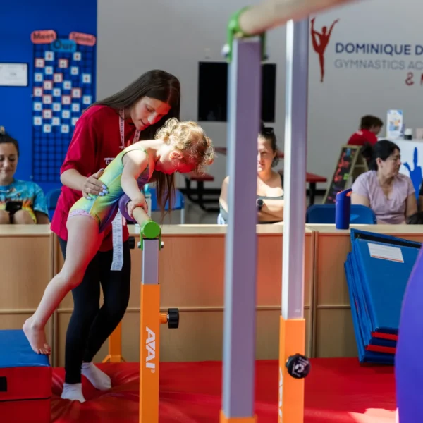 Coach training gymnast on bars