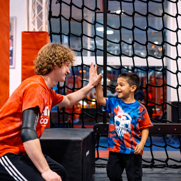 Coach gives kid high five after completing obstacle course at Ninja Summer Camp