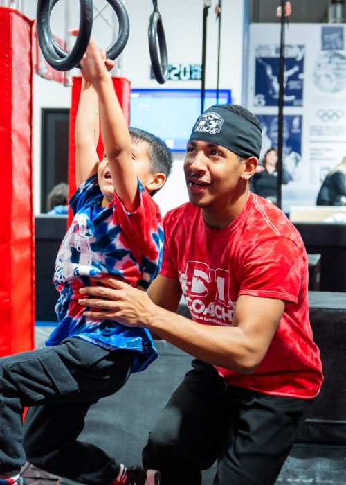 Coach helping child complete Ninja Summer Camp obstacle course