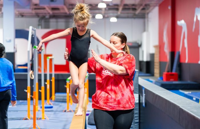 Child learning gymnastics with expert help from an instructor.