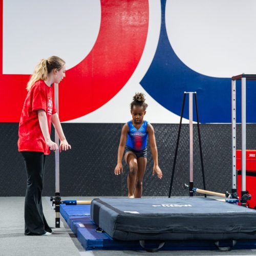young child learning gymnastics moves on a mat with a coach