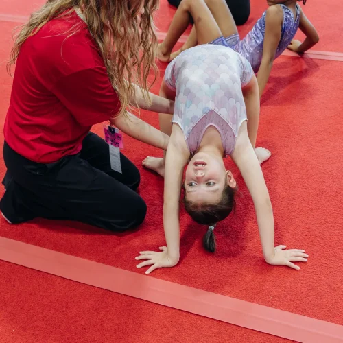 Coach spotting gymnast on back walkover