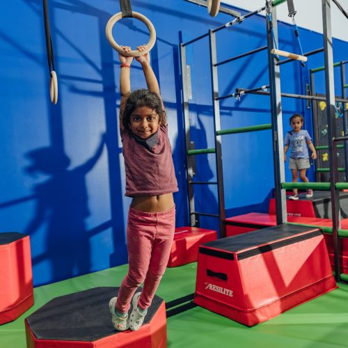 Little girl hanging on ring during gymnastics class at Dominique Dawes Academy