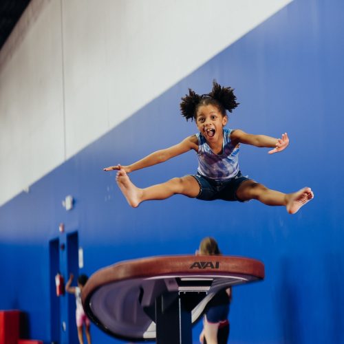 Little girl jumping in air during gymnastics class at Dominique Dawes Academy