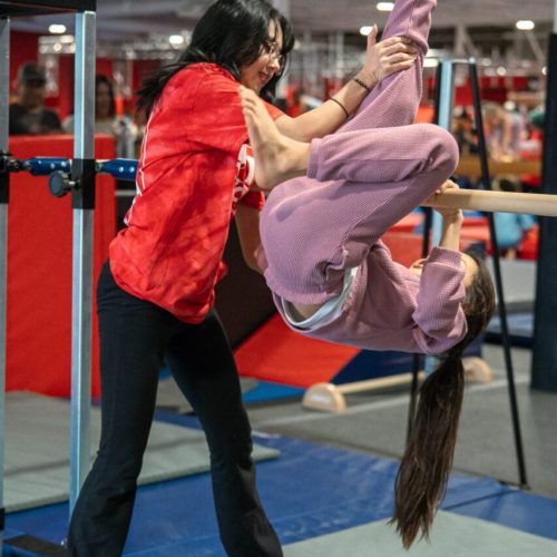 Gymnastics class with a teacher showing a student how to perform a move.
